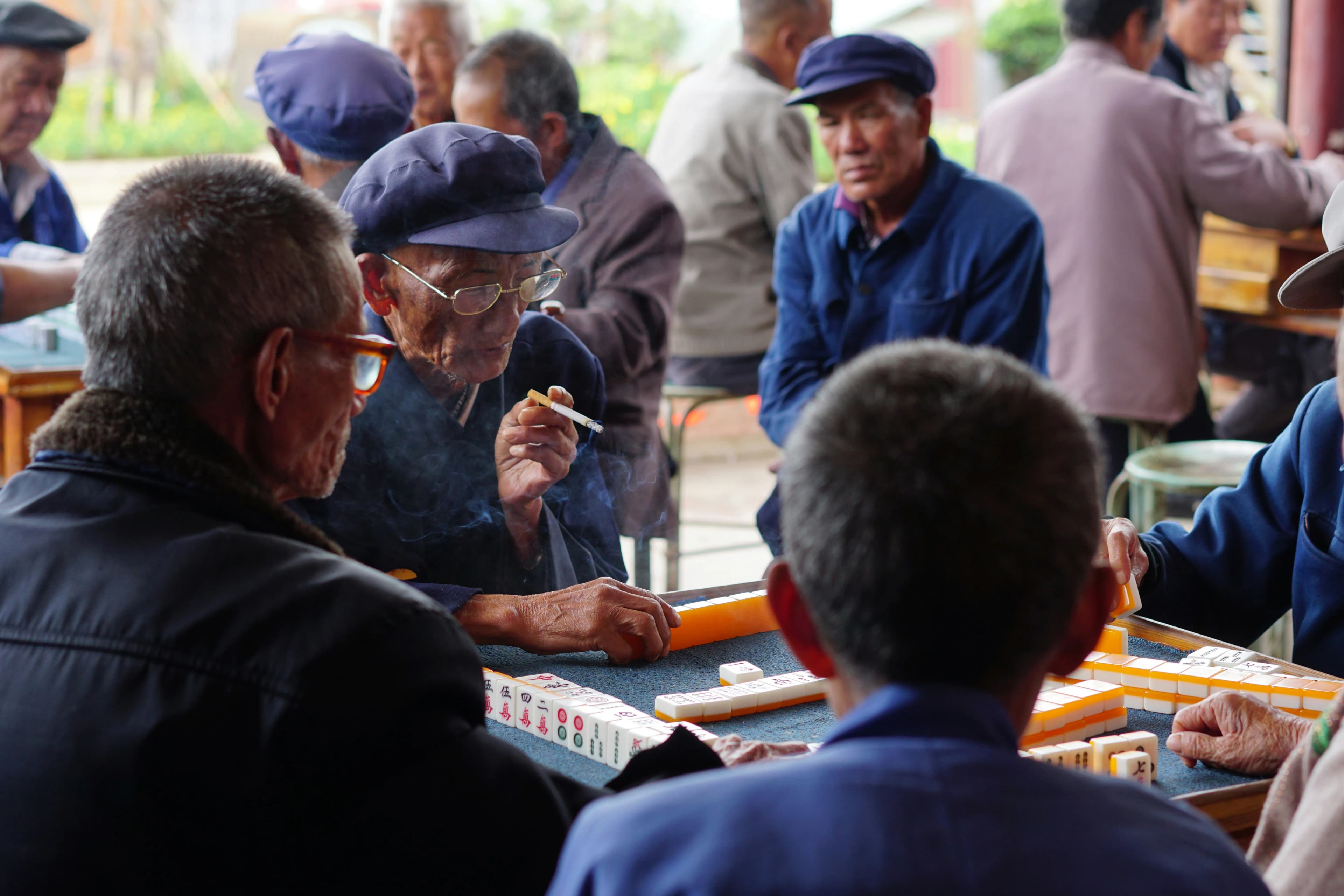 Grupo de hombres mayores chinos jugando al mahjong en un espacio público